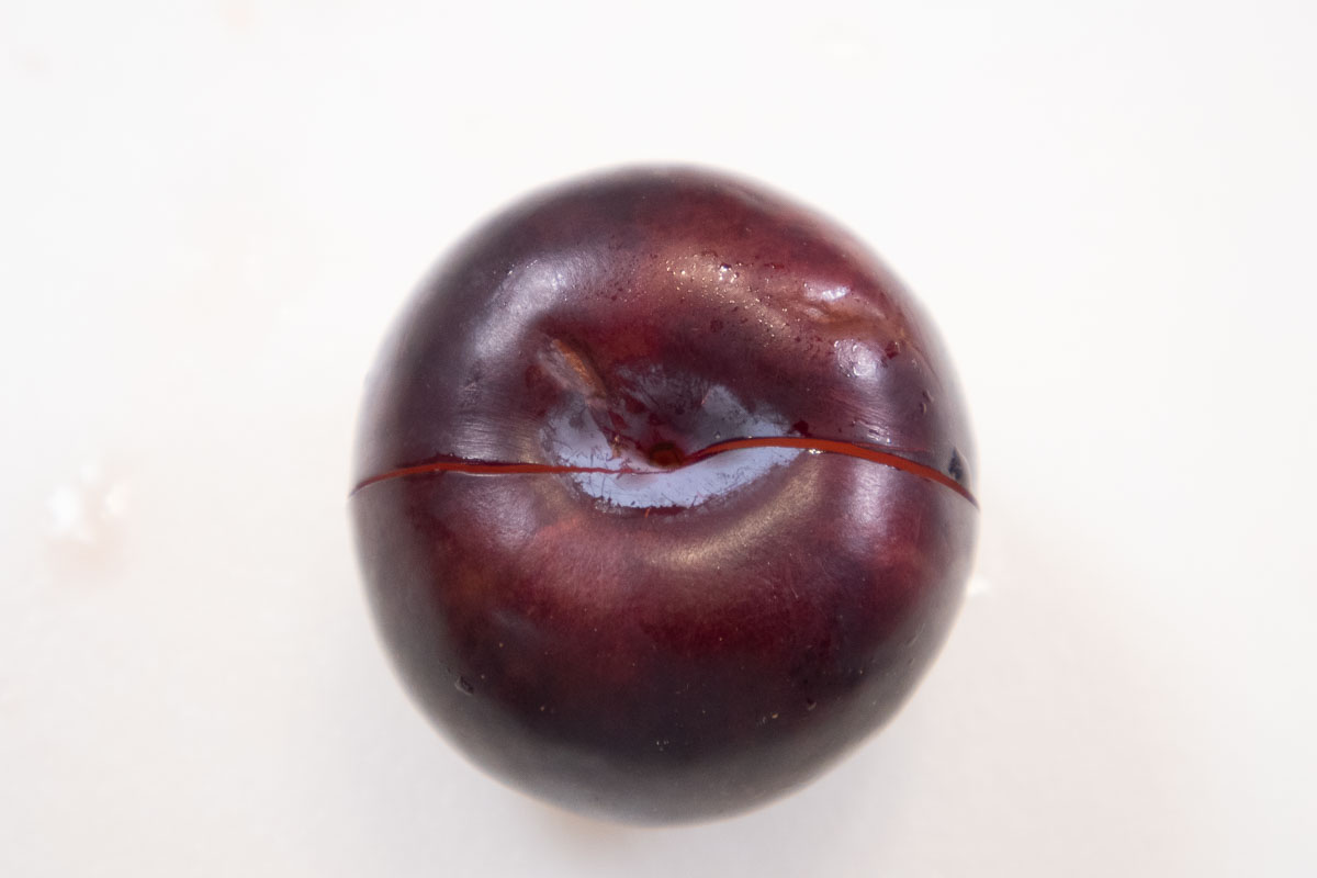 The plum is cut around it equator in order to separate it.