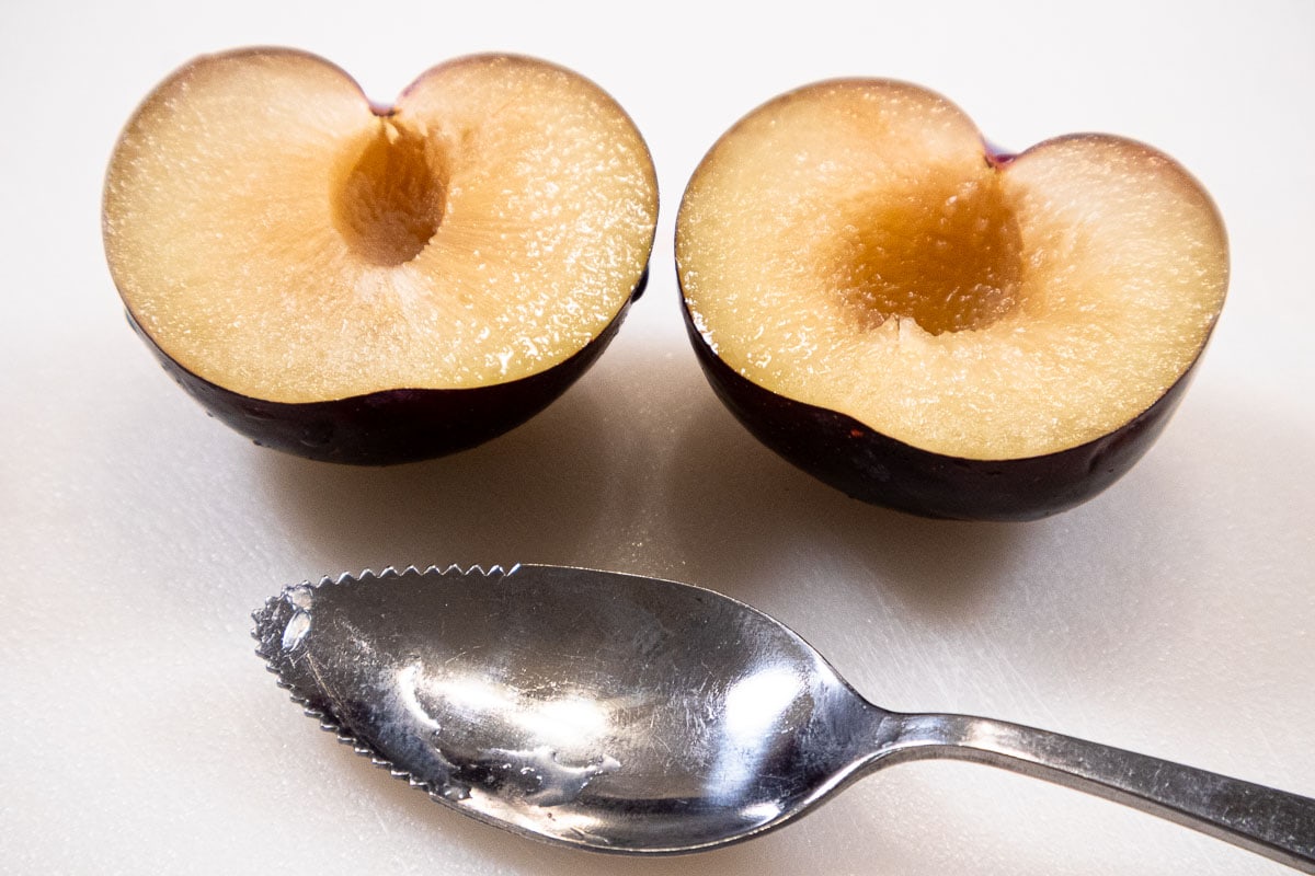 The pit of the plum is removed using a serrated spoon to make it easy.