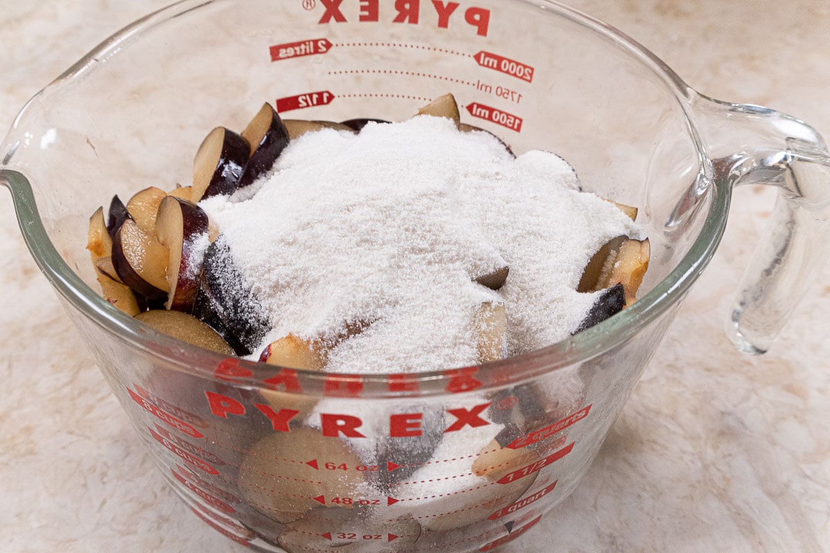 The dry ingredients (sugar, flour and salt) are added to the plums.