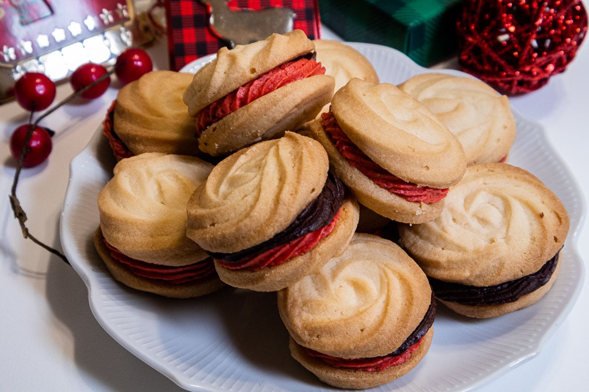 This photos shows the cookies on a white plate with holly berries and a red ball.