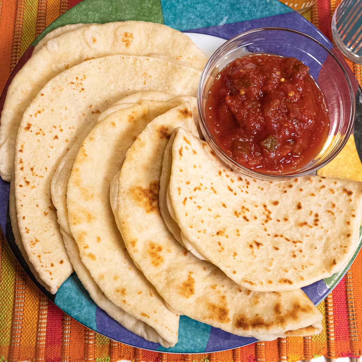 Buttermilk flatbreds on a colorful plate with a bowl of salsa.