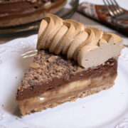 A slice of Banoffee Pie with coffee whipped cream sits on a white plate.