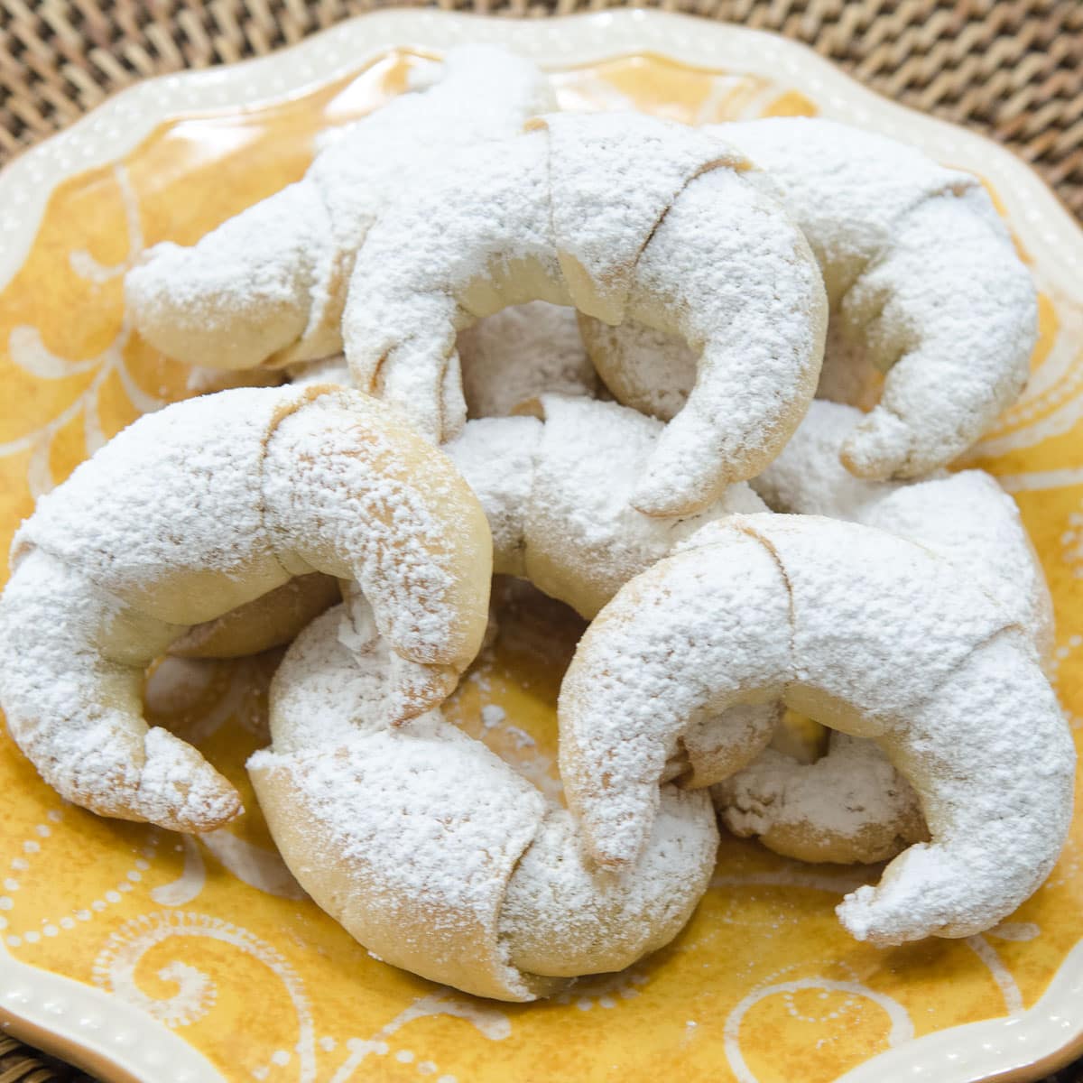 Crescent shaped sweetrolls filled with walnuts, cinnamon and sugar on a yellow plate.