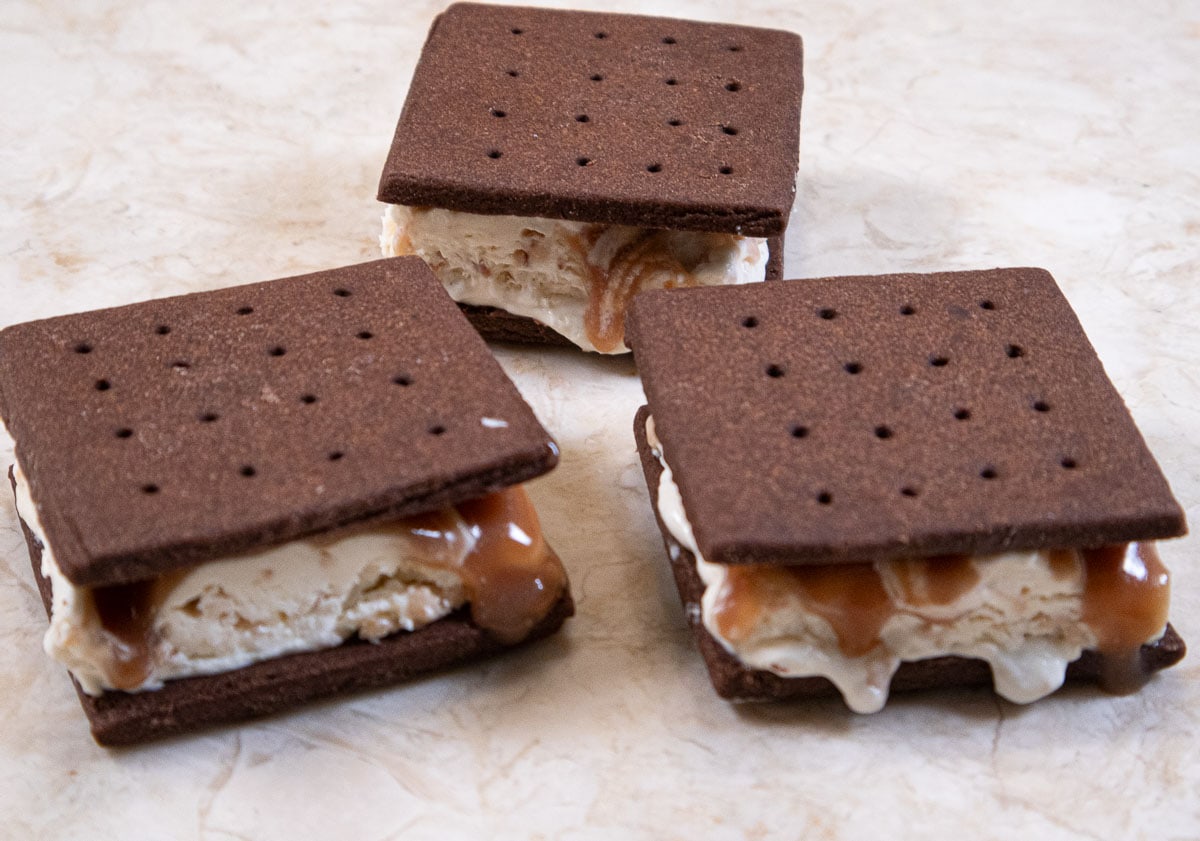 This picture features 3 completed ice cream sandwiches on a table.