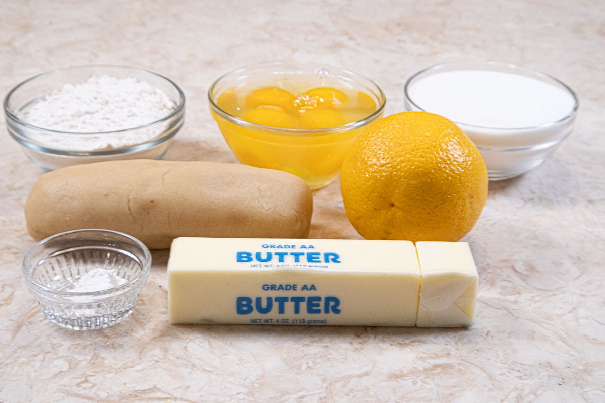 Ingredients for the Orange Almond Tea Cake include almond paste, granulatedsugar, unsalted butter, eggs, all-purpose flour, baking powder, and orange zest.