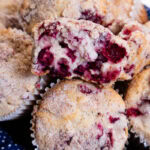 This photo shows an open cranberry vanilla muffin sitting on top of more muffins.