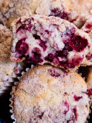 This photo shows an open cranberry vanilla muffin sitting on top of more muffins.