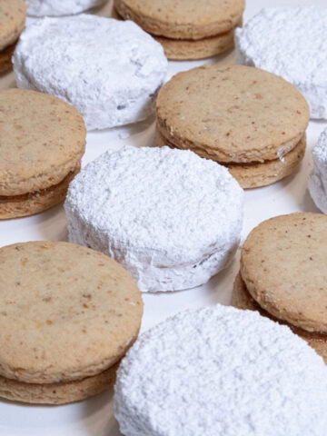 Rows of plain and powdered sugar Serbian Walnut Cookies on the diagonal are shown