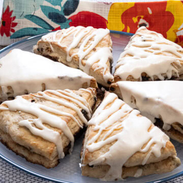 A plate of 6 Stuffed Buttermilk Scones on a blue rimmed plate with a multi colored napkin in the background.