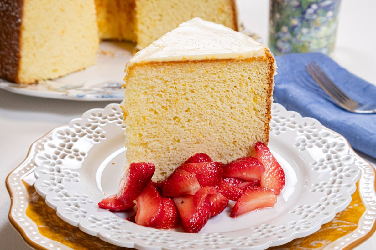 The bottom picture shows a slice of the chiffon cake with strawberries on a white, lace edge plat with the cut cake in the background, a blue napkin and a coffee cup in the background.  