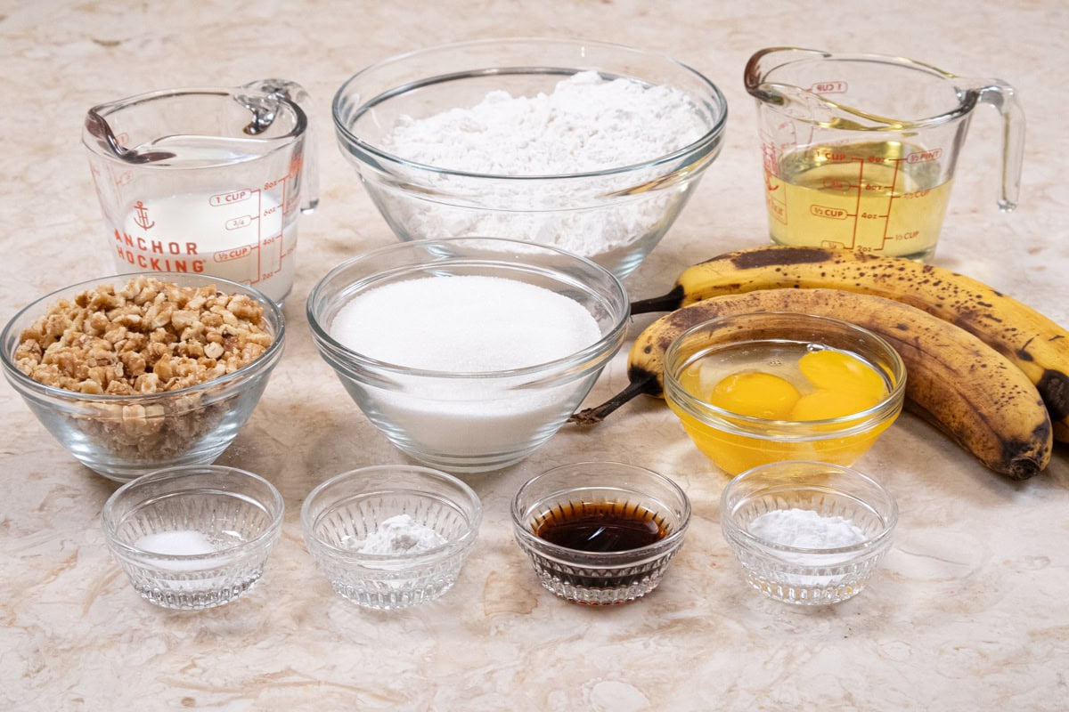 Ingredients for the banana bread include banana puree, buttermilk, eggs,  baking powder, vanilla, sugar, cake flour vegetable oil, baking soda, and, salt. (The nuts in the photo are omitted for this recipe).