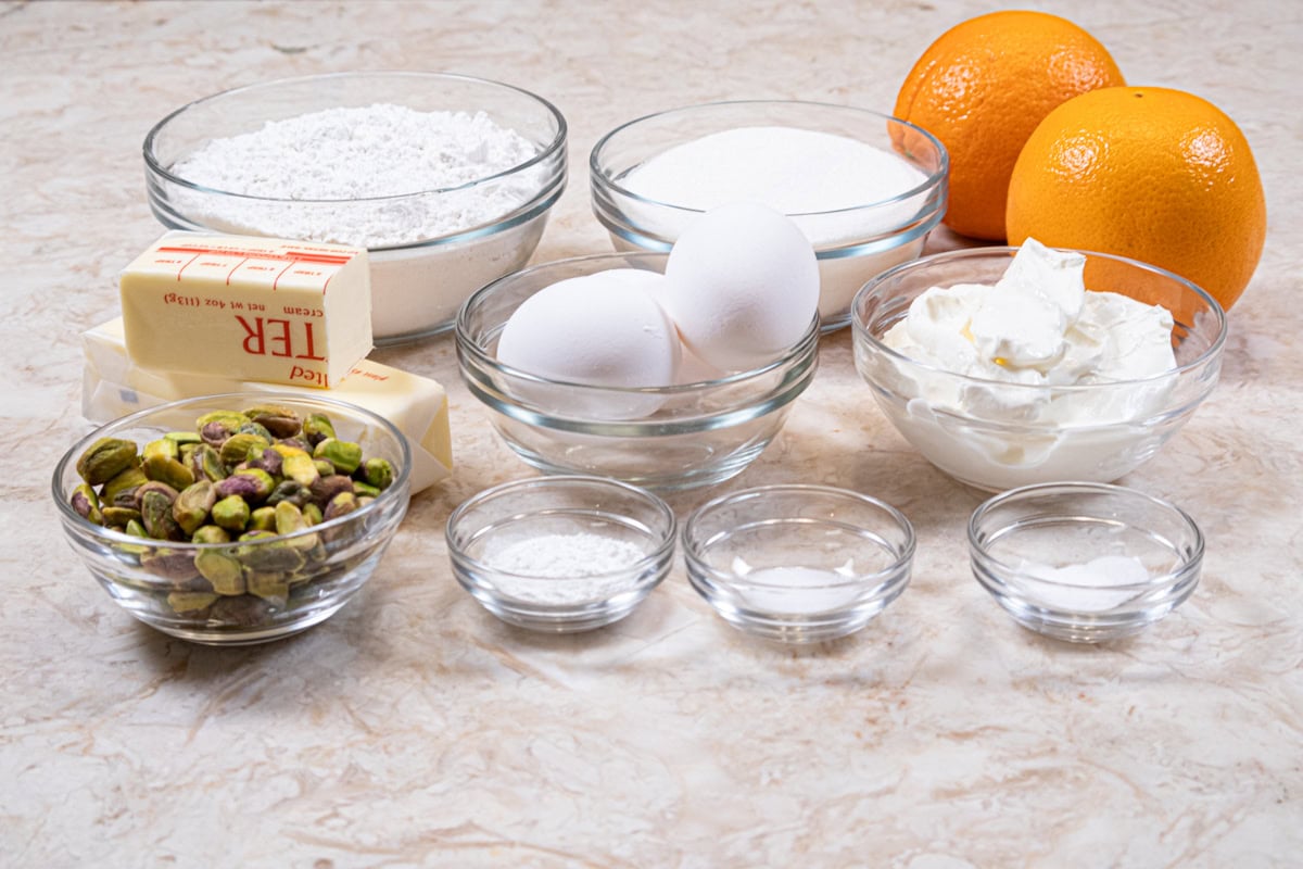 The ingredients for the loaf cake include cake flour, baking powder, baking soda, salt, unsalted butter, granulate sugar, orange zest, eggs, sour cream and pistachio nuts.  