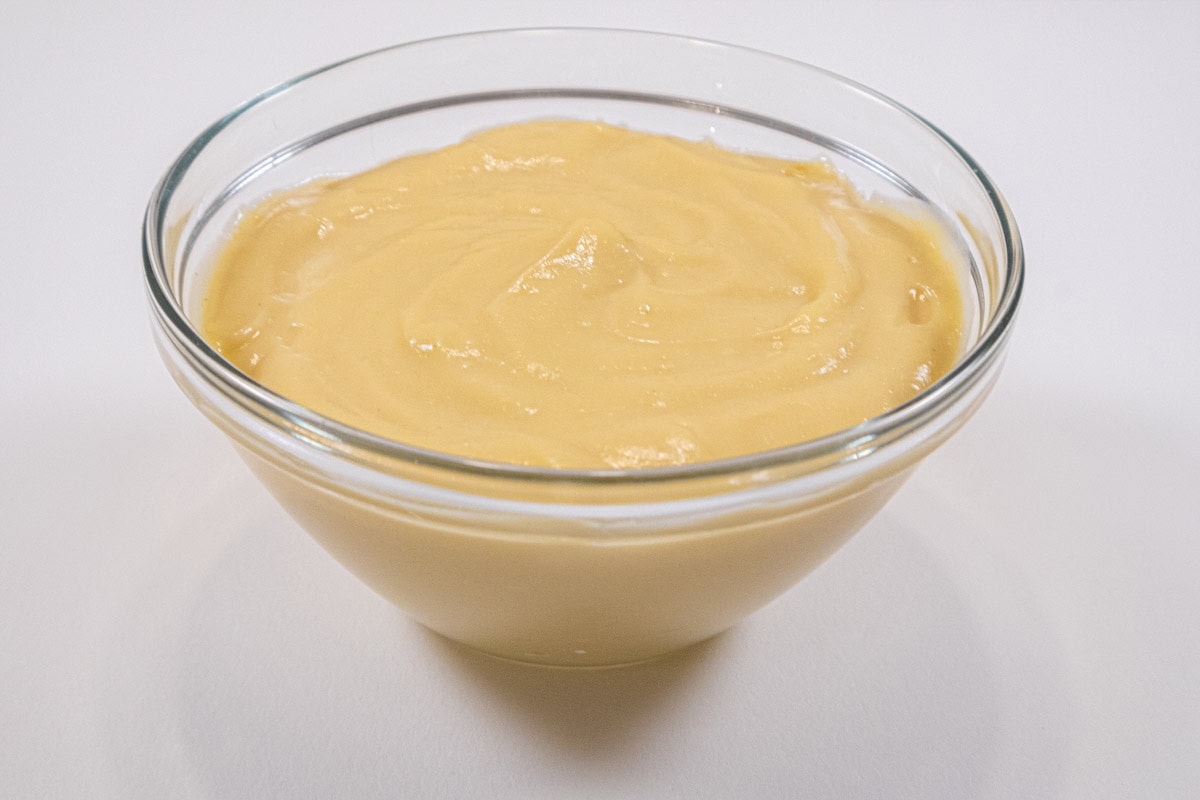 A bowl of pastry cream sits on a white background. 
