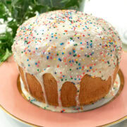 Easter Bread sits on a peach rimmed plate with a green plant in the background.