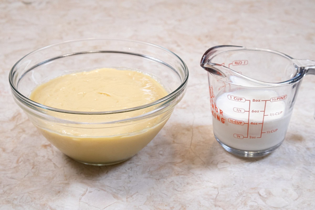 Lightened pastry cream ingredients are pastry cream in a bowl and heavy  cream in a measuring cup.  