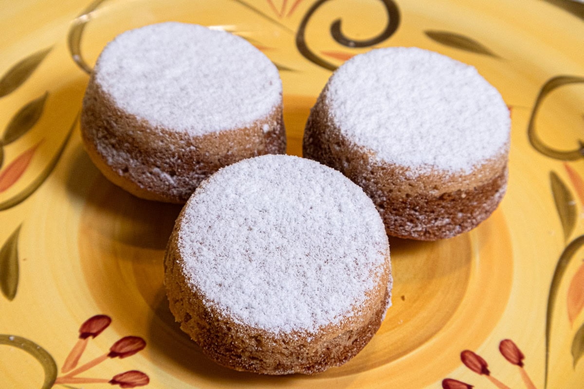 Three donuts made in muffin pasn are on on a yellow plate with olive green trim. 