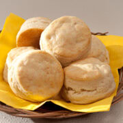 A basket lined wth a yellow napkin is filled with Cream Biscuits.