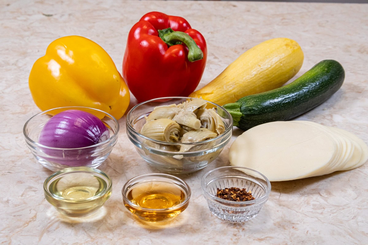 Ingredients for the vegetable filling are red and yellow peppers, zucchini, yellow squash, red onion, canola oil, balsamic vinegar, artichoke quarters, provolone cheese ad crush red pepper flakes. 