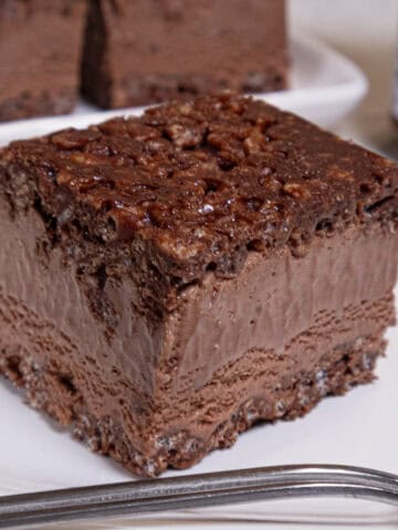 A Nutella Ice Cream Square sits on a w hite plate with more squares behind it and a nutella jar to the side.
