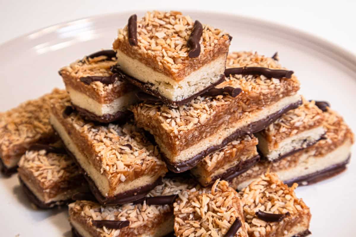 A stack of Samoa Bars sits on a cream colored plate.