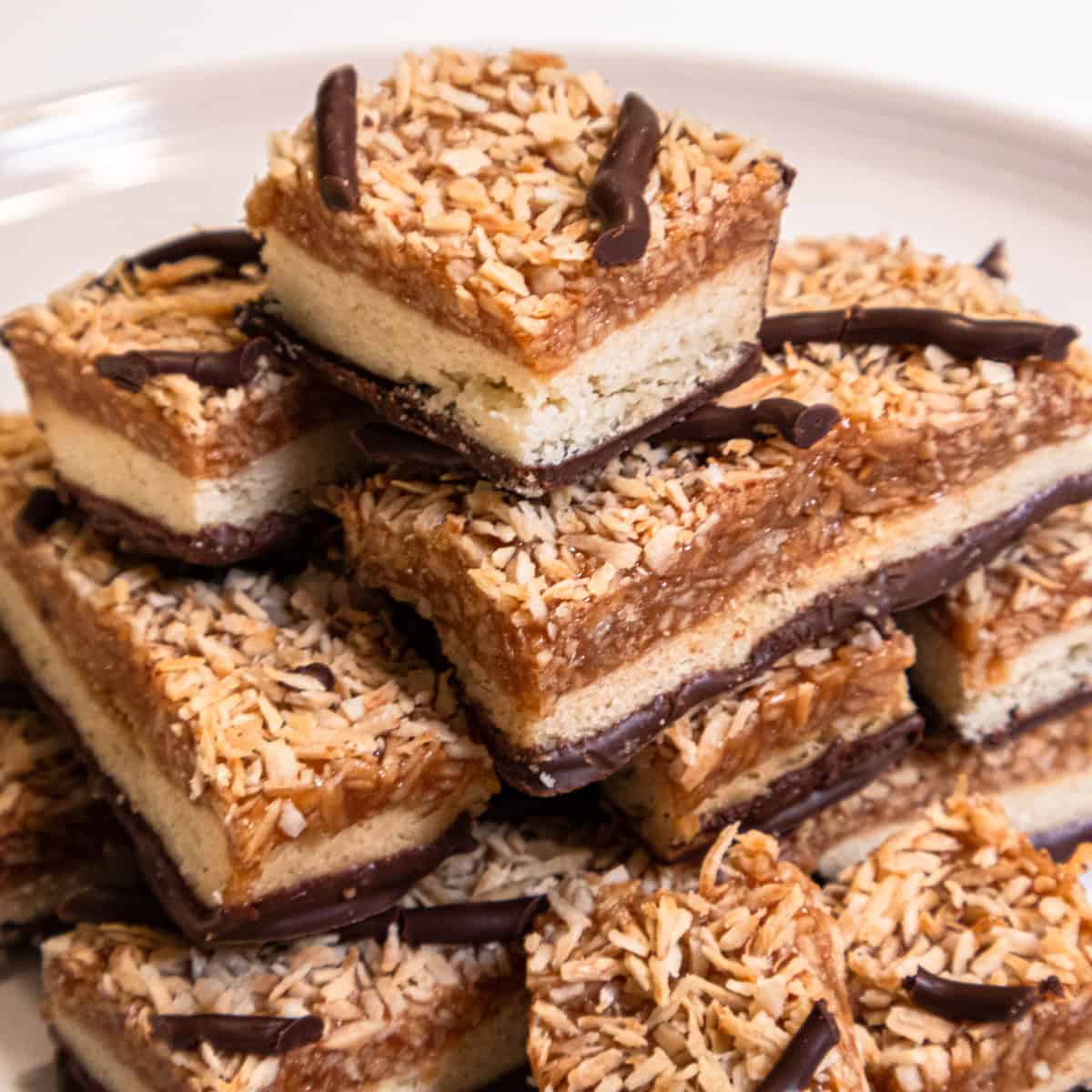 A stack of Samoa Bars sits on a cream colored plate.