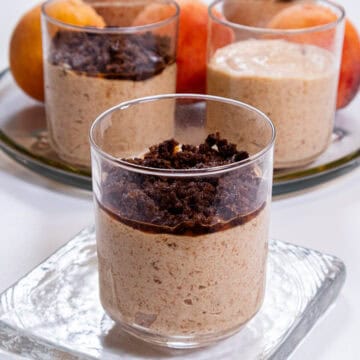 A picture of a single Peach Mousse with Cinnamon Crunch on a clear plate with a tray in the background,