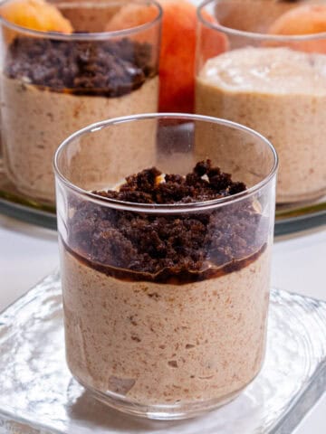 A picture of a single Peach Mousse with Cinnamon Crunch on a clear plate with a tray in the background,