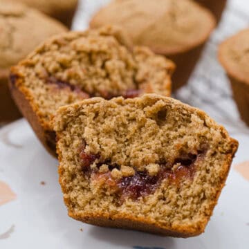 This is a close up of an open Peanut Butter and Jam Muffin with a riverlut of strawberry jam running through it.