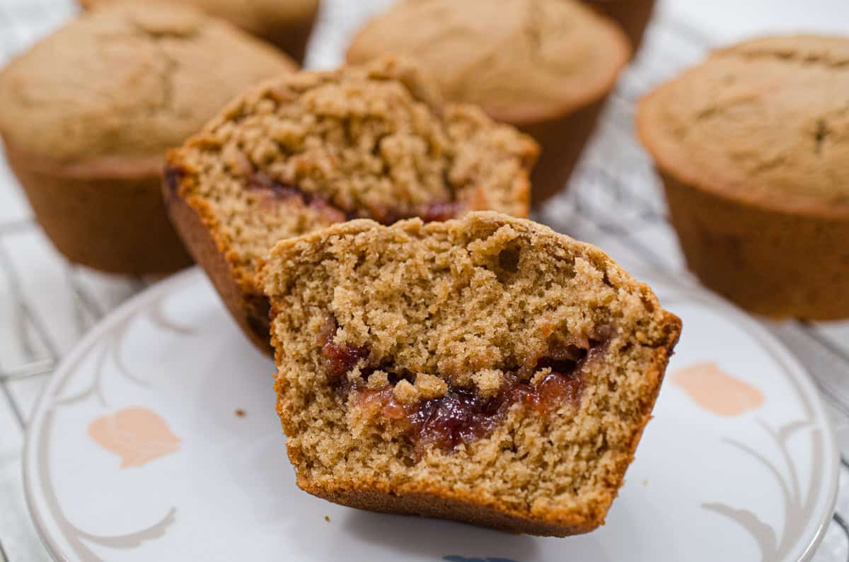 This is a close up of an open Peanut Butter and Jam Muffin with a riverlut of strawberry jam running through it.
