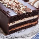 Three layers of chocolate cake, white chocolate mousse,dark chocolate mousse and a chocolate glaze sit on an old fashioned cut glass tray.