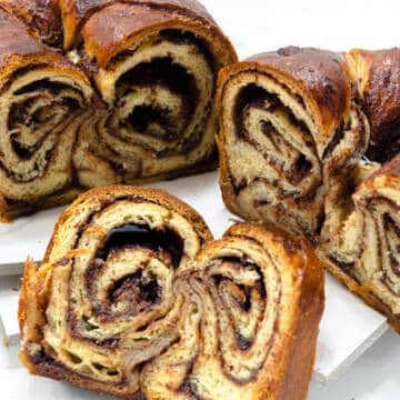 Several slices of the swirly Chocolate Babka is shown along with the whole in the background.