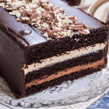 Three layers of chocolate cake, white chocolate mousse,dark chocolate mousse and a chocolate glaze sit on an old fashioned cut glass tray.