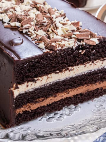 Three layers of chocolate cake, white chocolate mousse,dark chocolate mousse and a chocolate glaze sit on an old fashioned cut glass tray.