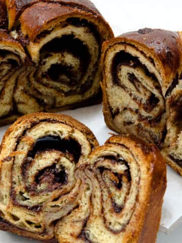 Several slices of the swirly Chocolate Babka is shown along with the whole in the background.