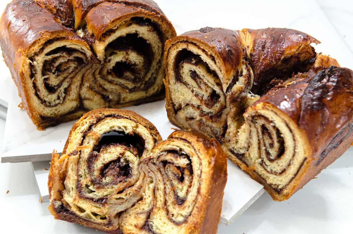 Several slices of the swirly Chocolate Babka is shown along with the whole in the background.