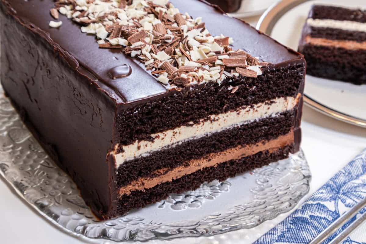 Three layers of chocolate cake, white chocolate mousse,dark chocolate mousse and a chocolate glaze sit on an old fashioned cut glass tray.