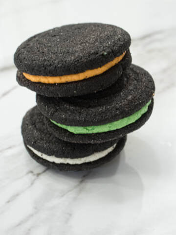 Almost Oreo cookies sit in a stack of 3 on a marble counter.