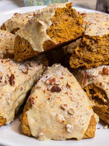 A plate of scones with one on top broken open to show the interior of the scone.