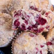 A basket of Cranberry Muffins with one split open on top.