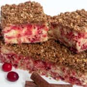 Squares of Cranberry Pecan Streusel Coffee cake with fresh cranberries and cinnamon sticks.