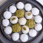A tray of White Chocolate Pistachio Cookies finished 4 different wasys its on a gray plate rimmed in gold.