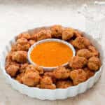 A white serving dish holds the Easy Cheesy Sausage Balls and dthe Apricot dipping sauce.