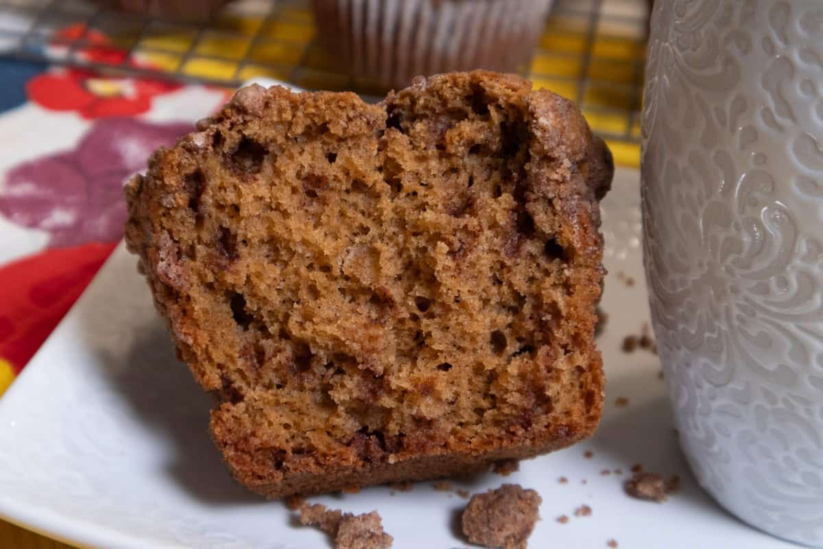 An open muffin on a white plate with muffins in the background.