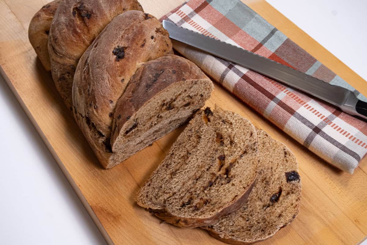 Bottom picture of the bread on a wooden board with a napkin and knife the background.