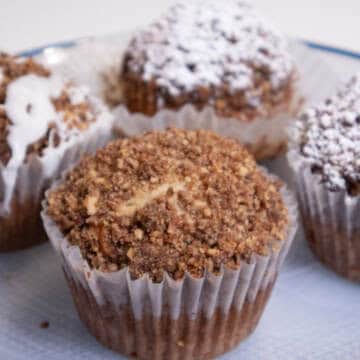 A Banana Streusel Muffin on aplate with others behind it.