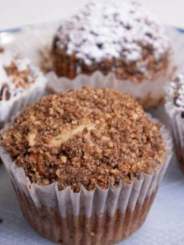 A Banana Streusel Muffin on aplate with others behind it.