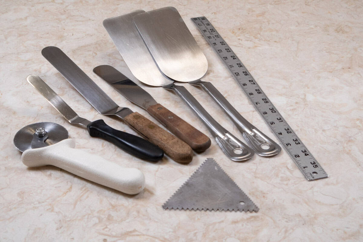 Equipment for filling and finishing a cake include a pizza cutter, small and large offset spatulas, a straight metal spatula, two pancake turners and a ruller. 
