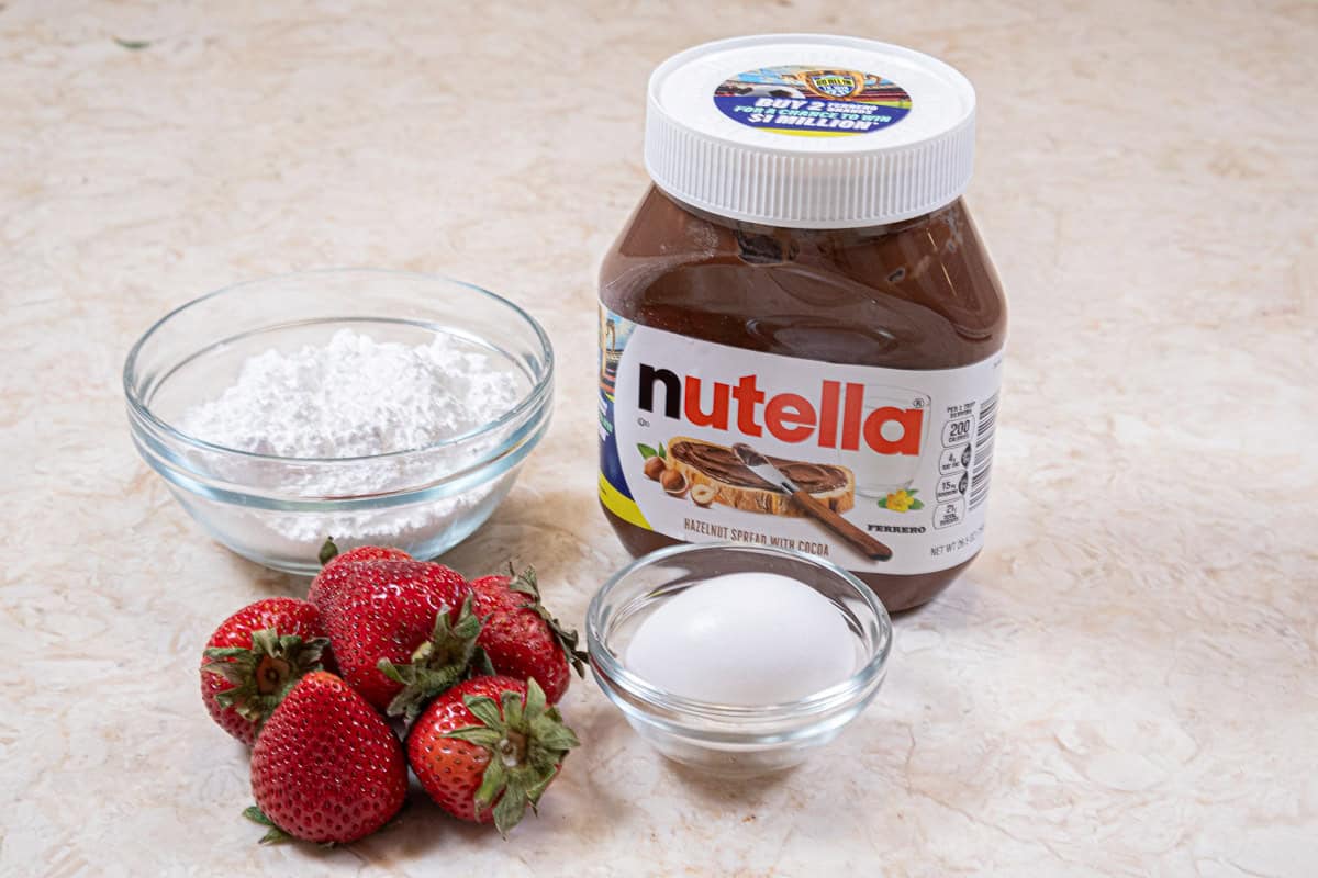 For the assembly the ingredients used are fresh strawberries, nutella, an egg, and powdered sugar. 