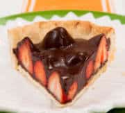 A lice of the Chocolate Strawberry Pie sits on a white and green plate with an orange runner behind it,