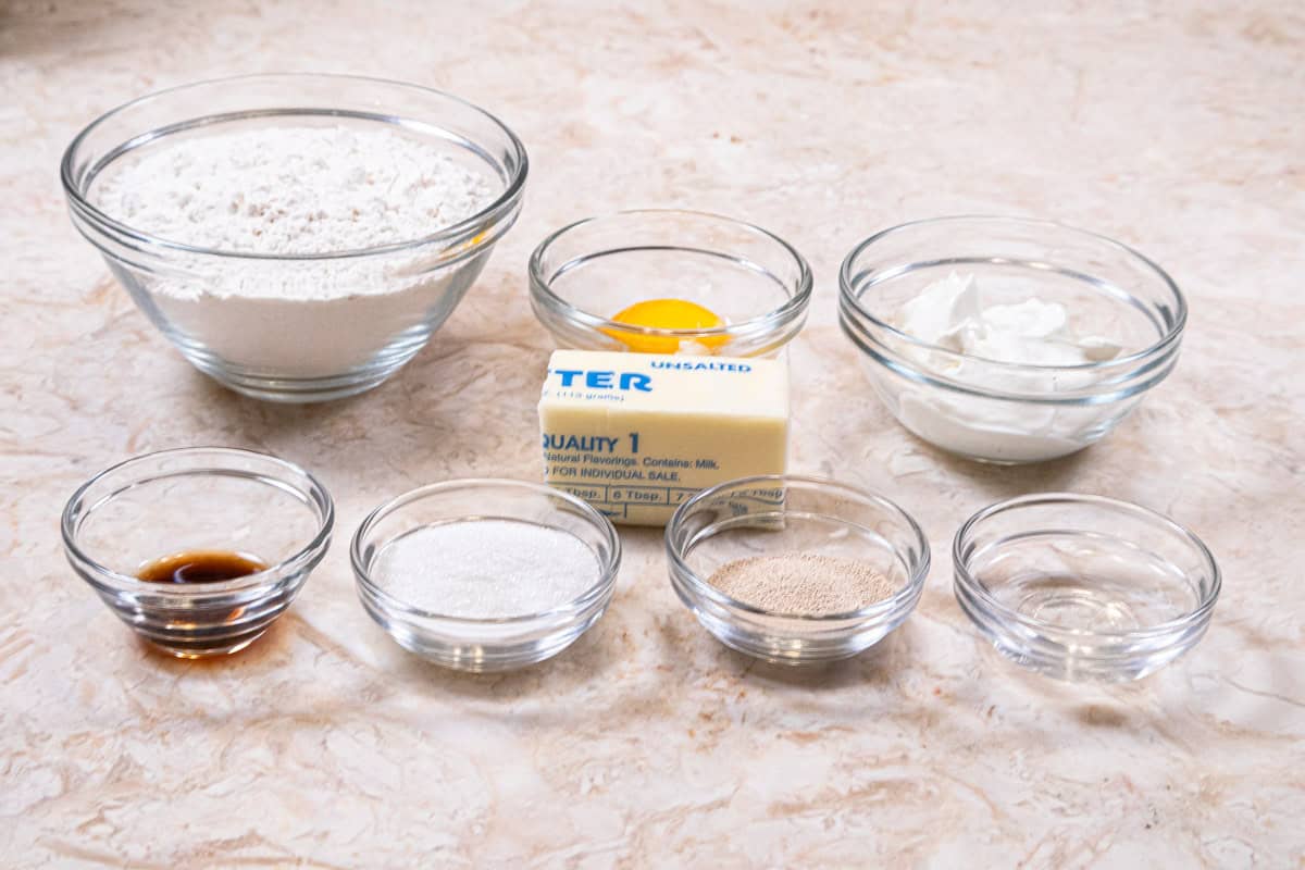 Ingredients for the pastry dough are yeast,  all-purpose flour, unsalted butter, sour cream granulated sugar, egg yolk. vanilla extract and water
